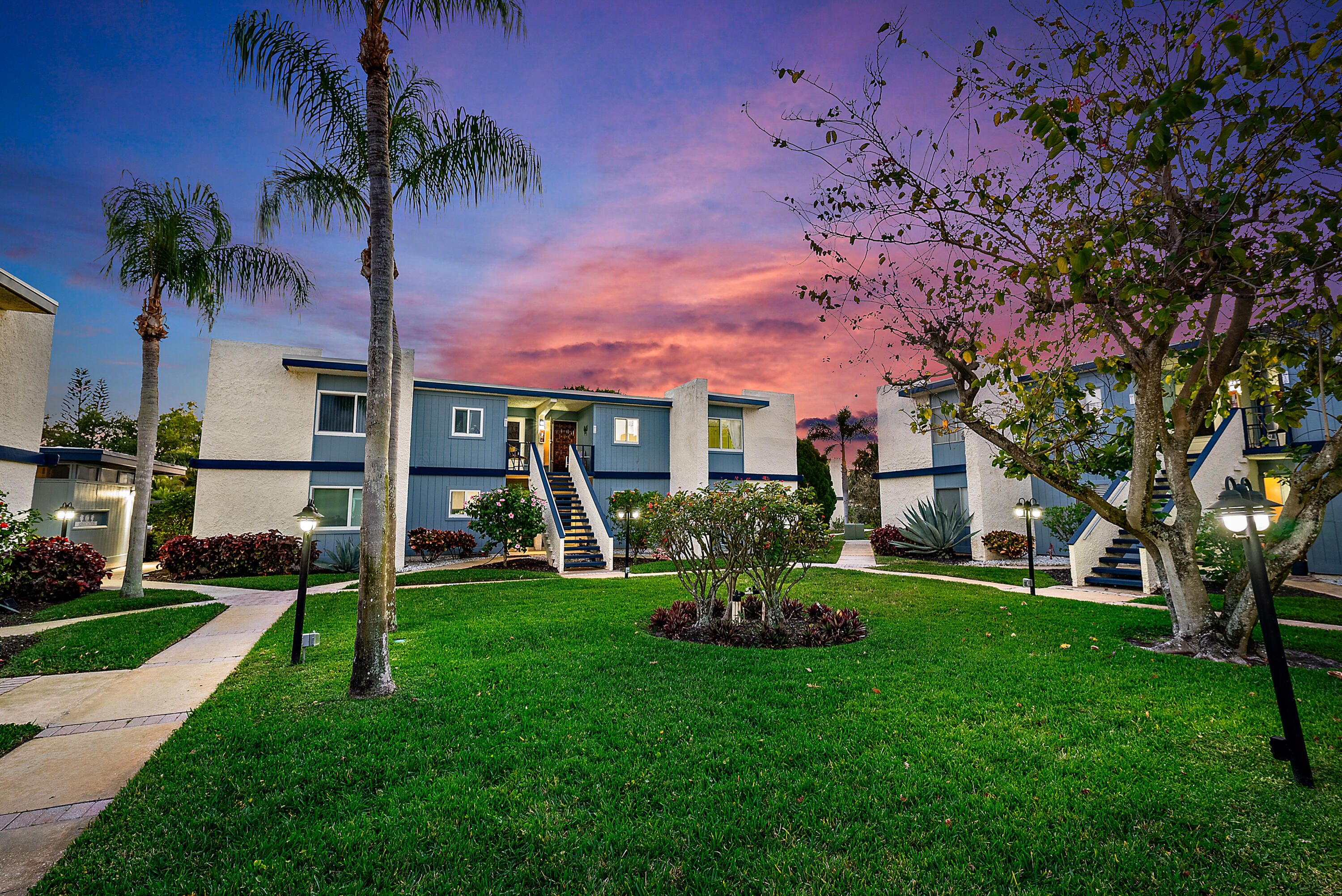 1561 Northeast 12th Terrace, Unit C14 Jensen Beach, FL 34957 - Photo 2 of 27 a front view of a house with garden and trees