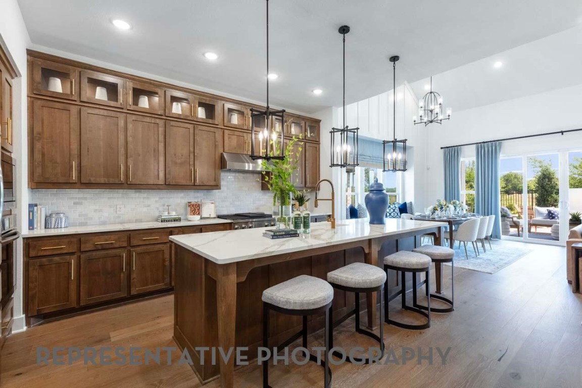 295 Sierra Stream Lane Conroe, TX 77304 - Photo 3 of 16 a kitchen with stainless steel appliances granite countertop a stove a sink a refrigerator a dining table and chairs with wooden floor