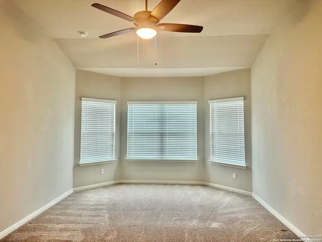 an empty room with fan and windows
