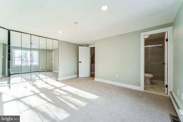 a view of an empty room and bathroom with a shower