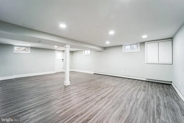 an empty room with wooden floor closet and windows
