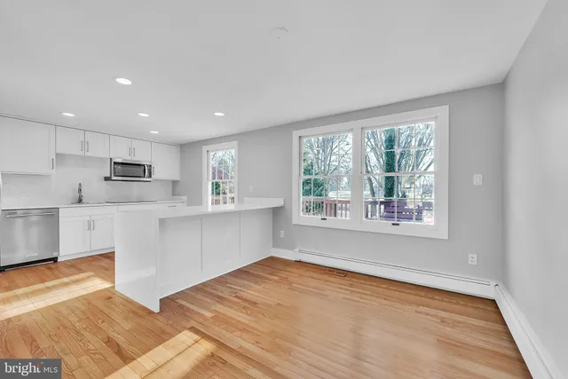 a open kitchen with white cabinets and wooden floor