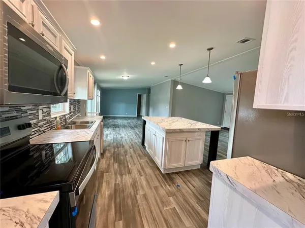 a large white kitchen with a stove a sink dishwasher and a microwave oven with large wooden cabinets