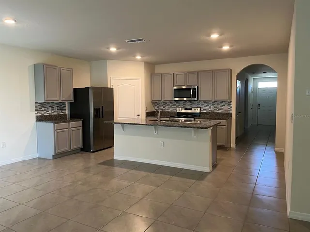 a kitchen with stainless steel appliances granite countertop a stove a refrigerator a sink a microwave and a refrigerator