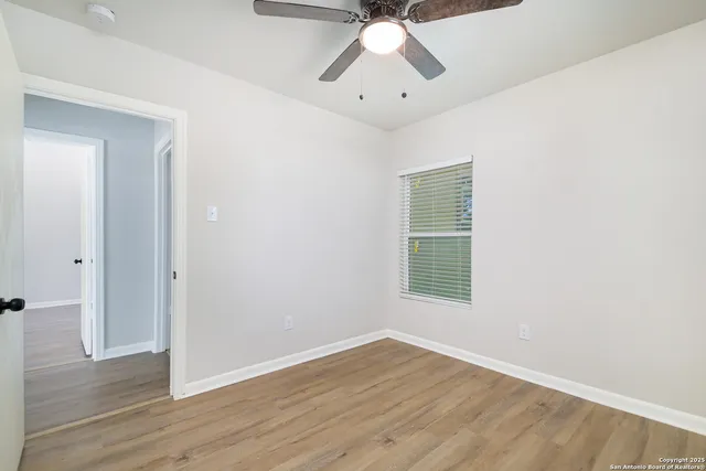 an empty room with wooden floor fan and windows