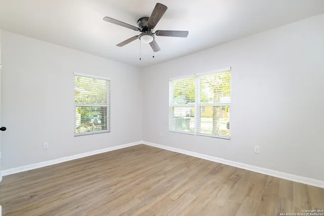 a view of an empty room with wooden floor and a window
