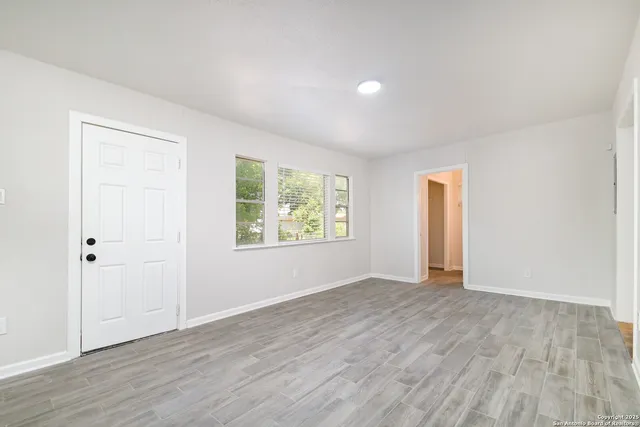 an empty room with wooden floor and windows