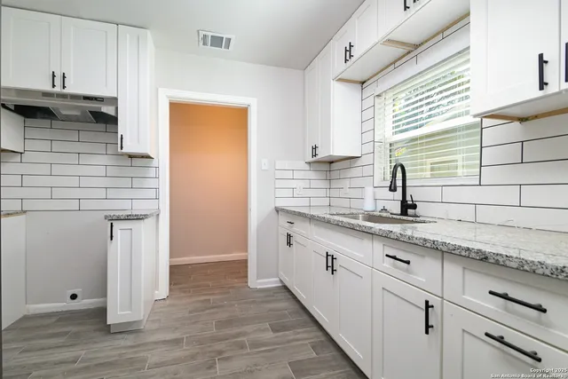 a kitchen with granite countertop white cabinets and sink