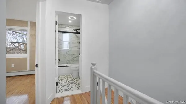a view of a hallway with wooden floor and a bathroom