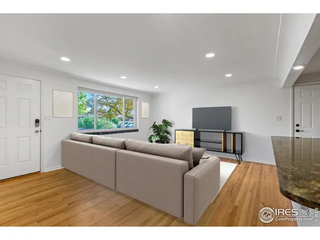 an empty room with wooden floor and fan