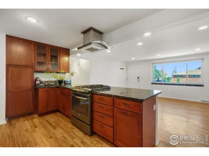 a kitchen with stainless steel appliances granite countertop a stove a sink and a refrigerator with wooden floor