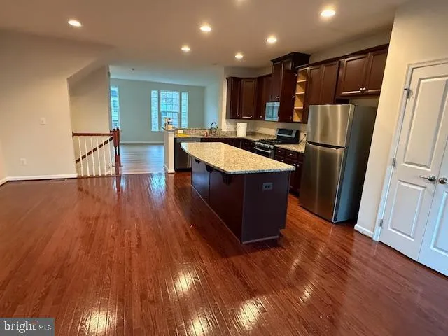 a kitchen with stainless steel appliances granite countertop a refrigerator a sink and wooden floors