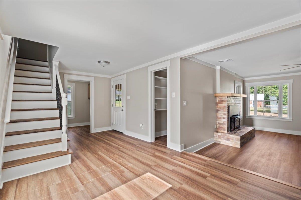 101 Sivil Circle Covington, TN 38019 - Photo 25 of 40 Unfurnished living room featuring a fireplace, stairs, crown molding, light wood-style flooring, and ceiling fan