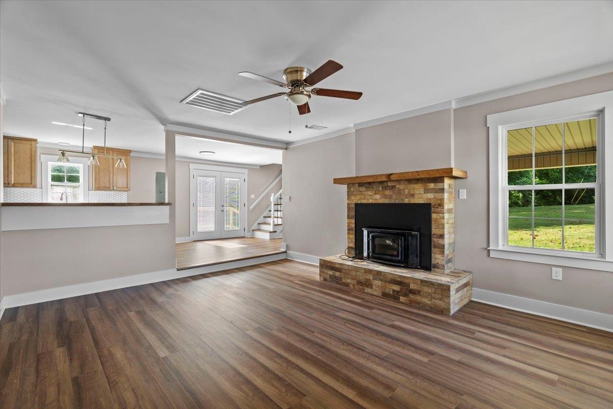 101 Sivil Circle Covington, TN 38019 - Photo 33 of 40 Unfurnished living room with stairs, dark wood-type flooring, ceiling fan, a fireplace, and crown molding