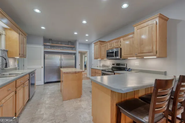 a kitchen with kitchen island a counter top space cabinets stainless steel appliances and a counter space