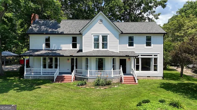 a view of a house with a yard and large tree