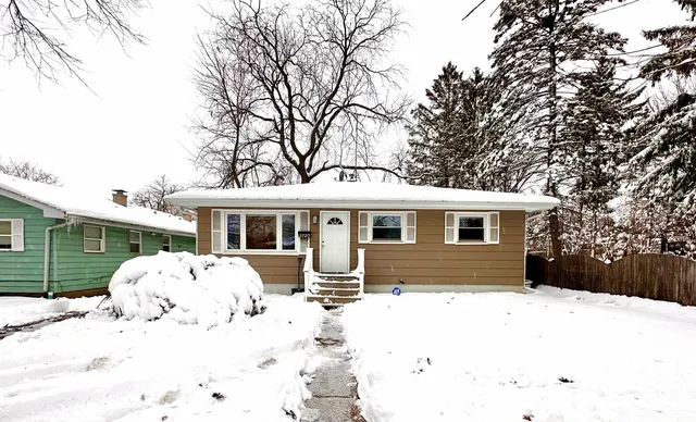 a front view of a house with a yard covered in snow