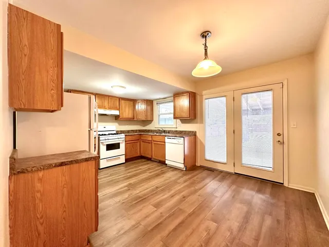 a kitchen with granite countertop a stove a sink dishwasher and a refrigerator with wooden floor