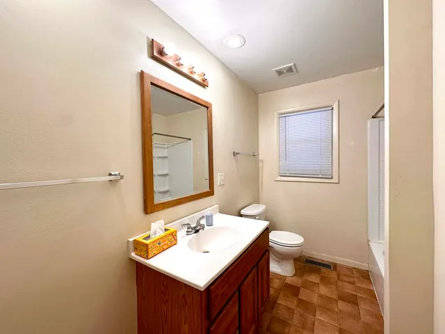 a bathroom with a sink mirror vanity and toilet