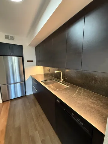 a kitchen with stainless steel appliances a sink dishwasher a refrigerator and wooden floor