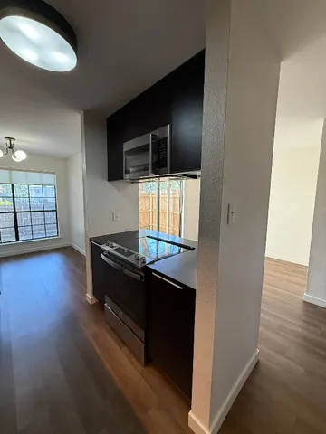 a kitchen with granite countertop a stove a microwave and a hard wood floor