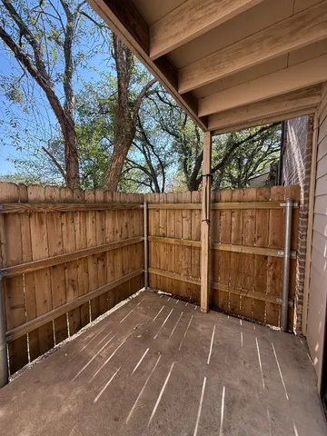 a view of backyard with large trees and wooden fence