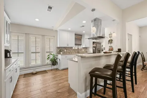 a kitchen with stainless steel appliances granite countertop a table chairs sink and cabinets