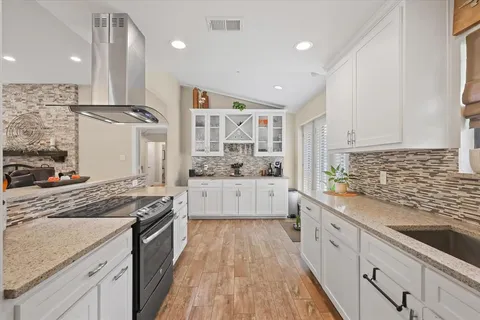 a large kitchen with stainless steel appliances kitchen island granite countertop a lot of counter space and wooden floors