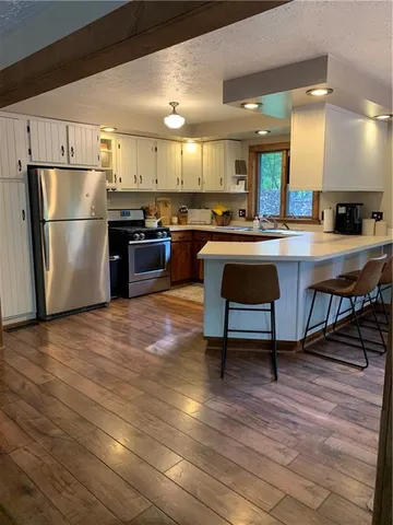 a kitchen with stainless steel appliances wooden floor and a refrigerator