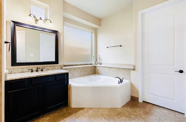 a bathroom with a bathtub a mirror and a sink