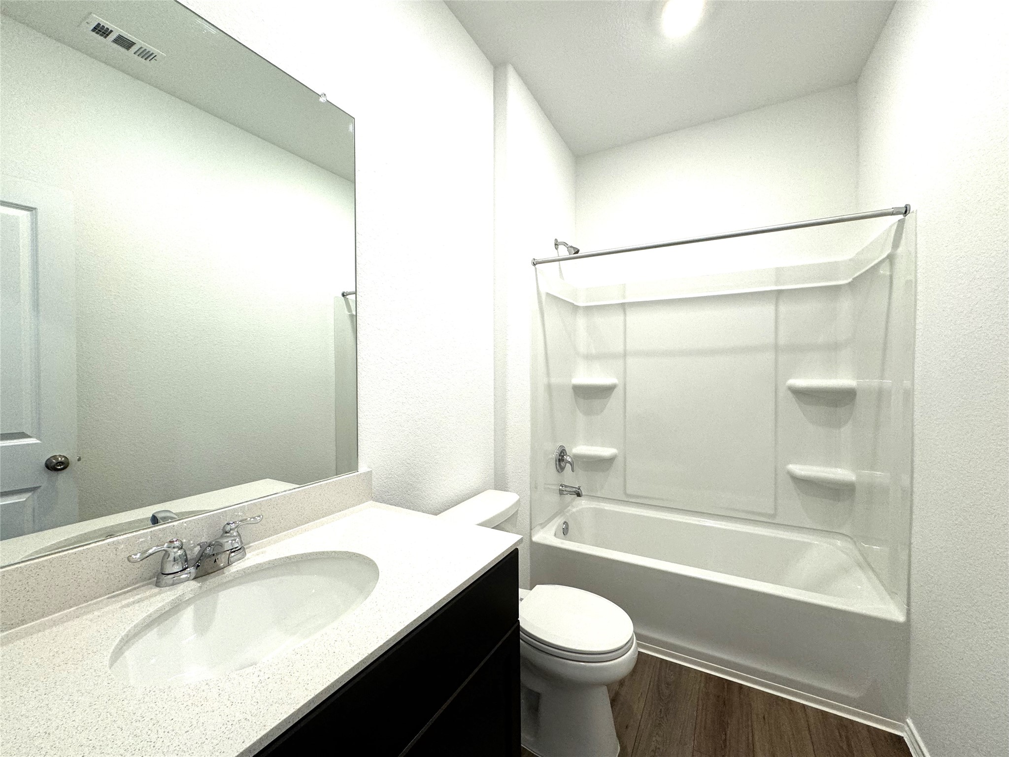 14408 Koti Way Pflugerville, TX 78660 - Photo 9 of 14 Bathroom featuring vanity, shower / washtub combination, dark wood-style floors, and a textured wall