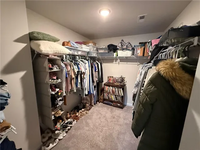 a view of walk in closet with clothes and shoes