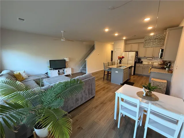 a living room with furniture kitchen view and a wooden floor