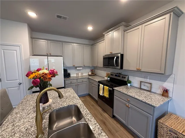 a kitchen with granite countertop a sink stainless steel appliances and cabinets