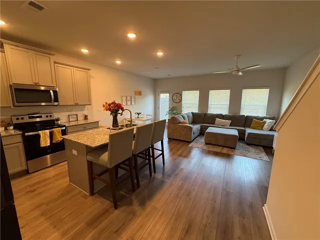 a living room with furniture kitchen view and a wooden floor
