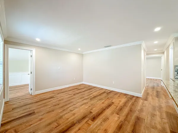 a view of kitchen and empty room with wooden floor