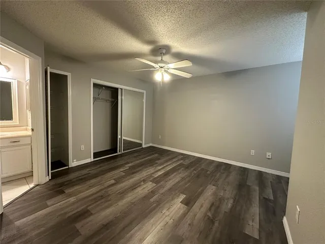 an empty room with closet and a ceiling fan