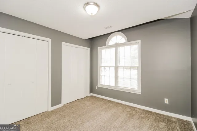 an empty room with windows and closet