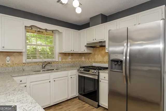 a kitchen with stainless steel appliances granite countertop a sink stove and refrigerator