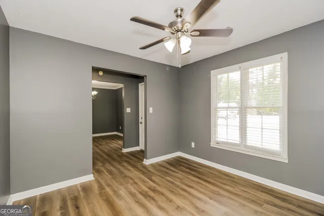 a view of an empty room with wooden floor and a window