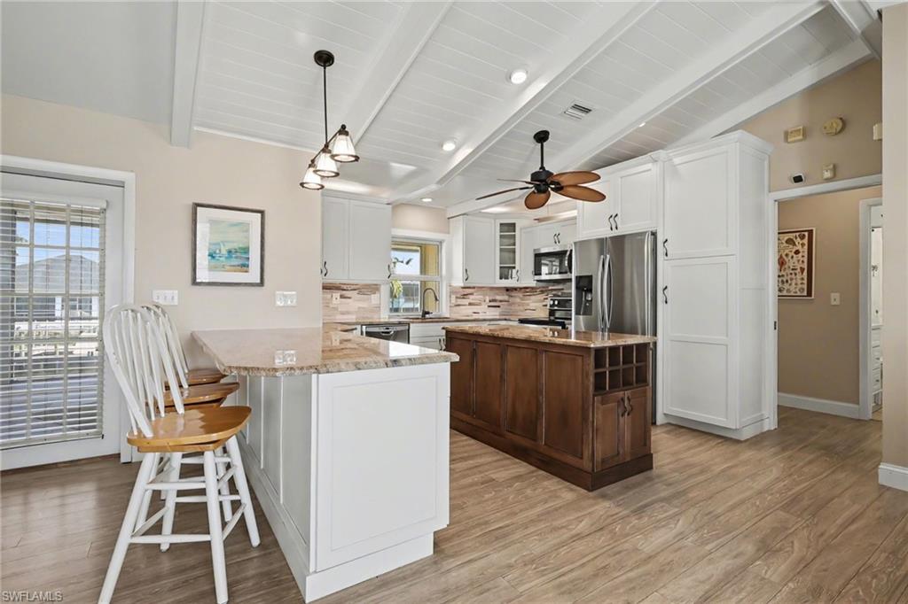 4838 Gary Road Bonita Springs, FL 34134 - Photo 14 of 29 a kitchen with stainless steel appliances kitchen island granite countertop a refrigerator a stove top oven a sink dishwasher and white cabinets with wooden floor