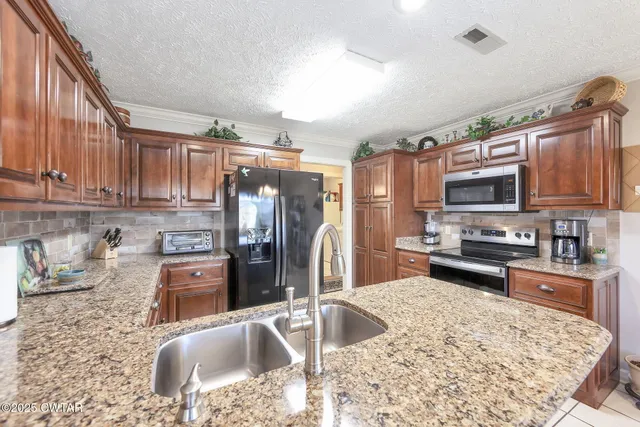 a kitchen with granite countertop a refrigerator stove and sink