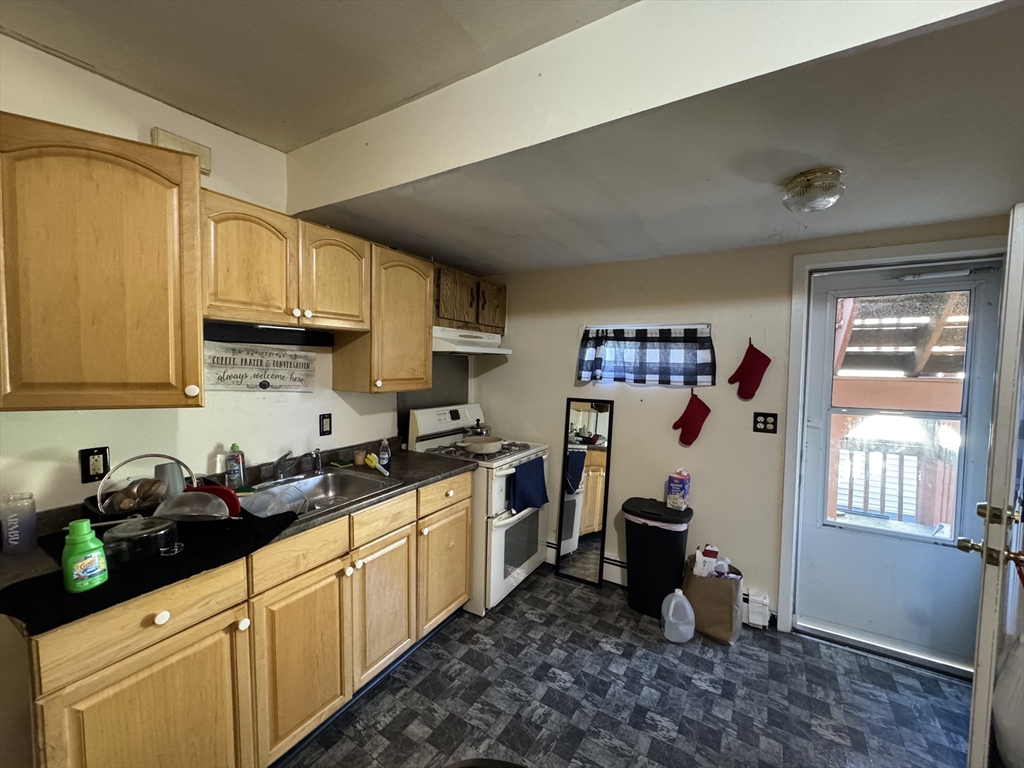28 Grand Street Lowell, MA 01851 - Photo 9 of 23 a kitchen with stainless steel appliances a sink a stove a refrigerator cabinets and a window