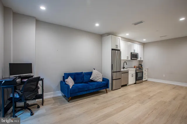 a living room with stainless steel appliances kitchen island granite countertop a couch and a view of kitchen