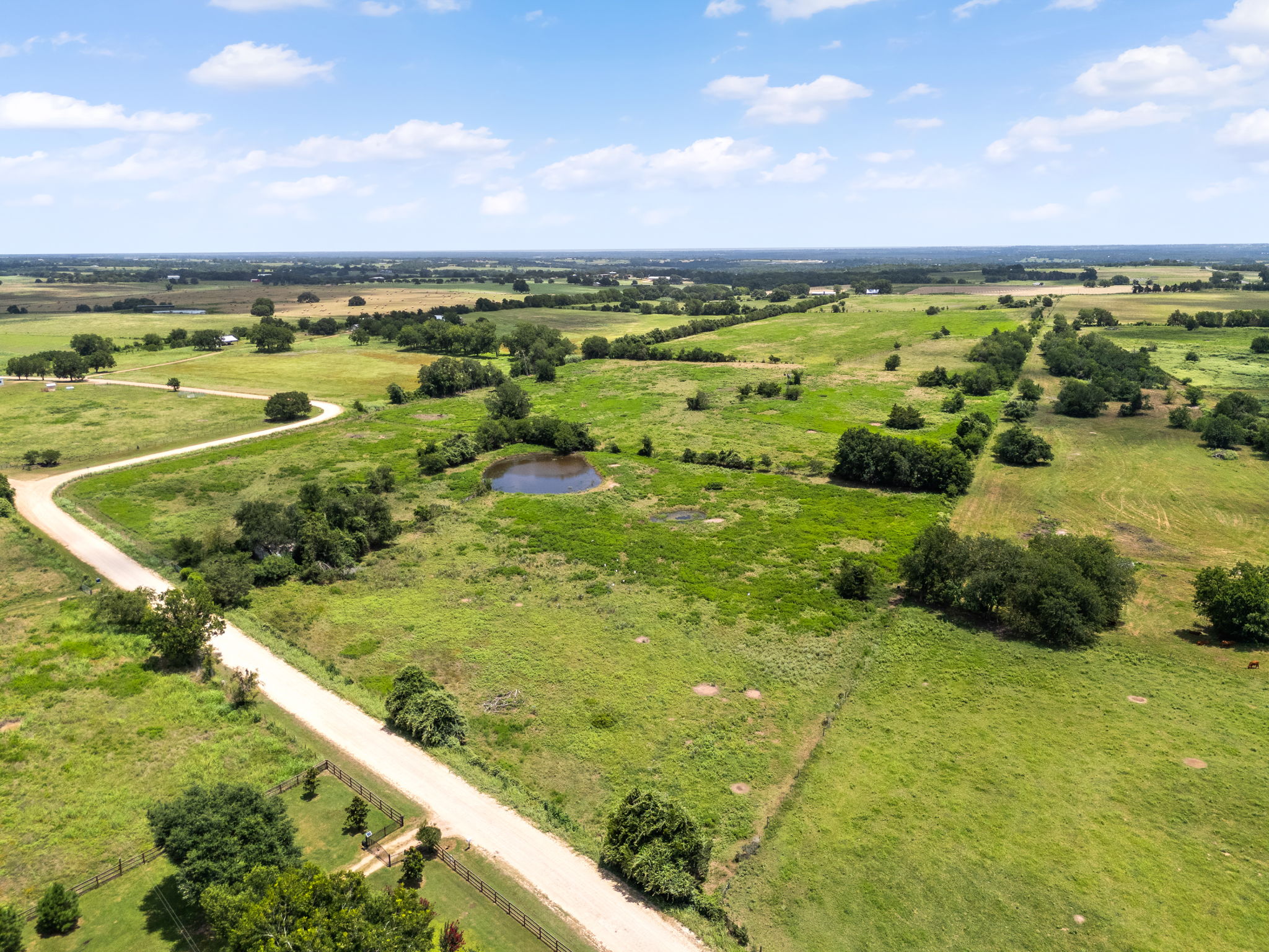 0 Thielemann Road Industry, TX 78944 - Photo 36 of 40 Rolling green acreage with a winding road and a tranquil pond awaits your vision.