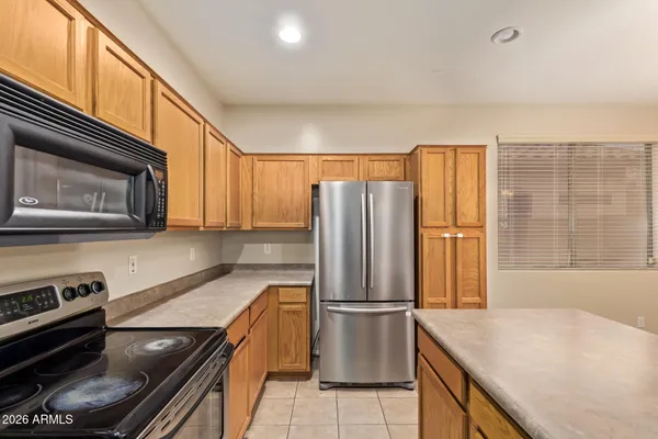 a kitchen with stainless steel appliances granite countertop a refrigerator a stove and a sink with wooden cabinets