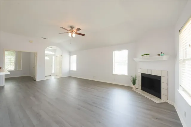 an empty room with windows fireplace and a sink