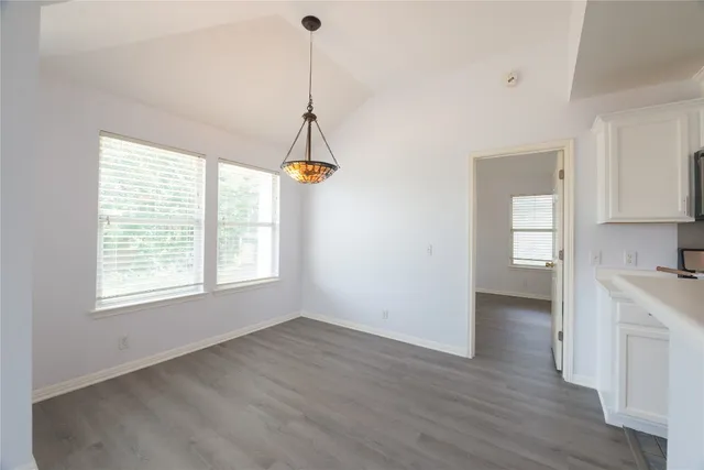 a view of empty room with wooden floor and window