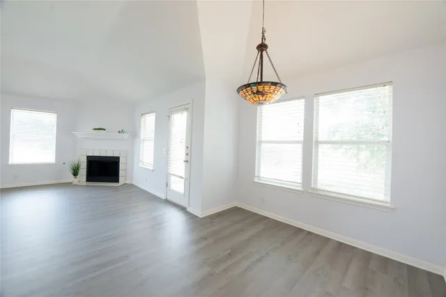 an empty room with wooden floor windows and a chandelier