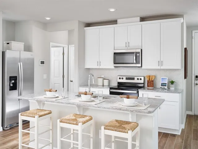 a kitchen with stainless steel appliances kitchen island granite countertop a stove a sink and a refrigerator